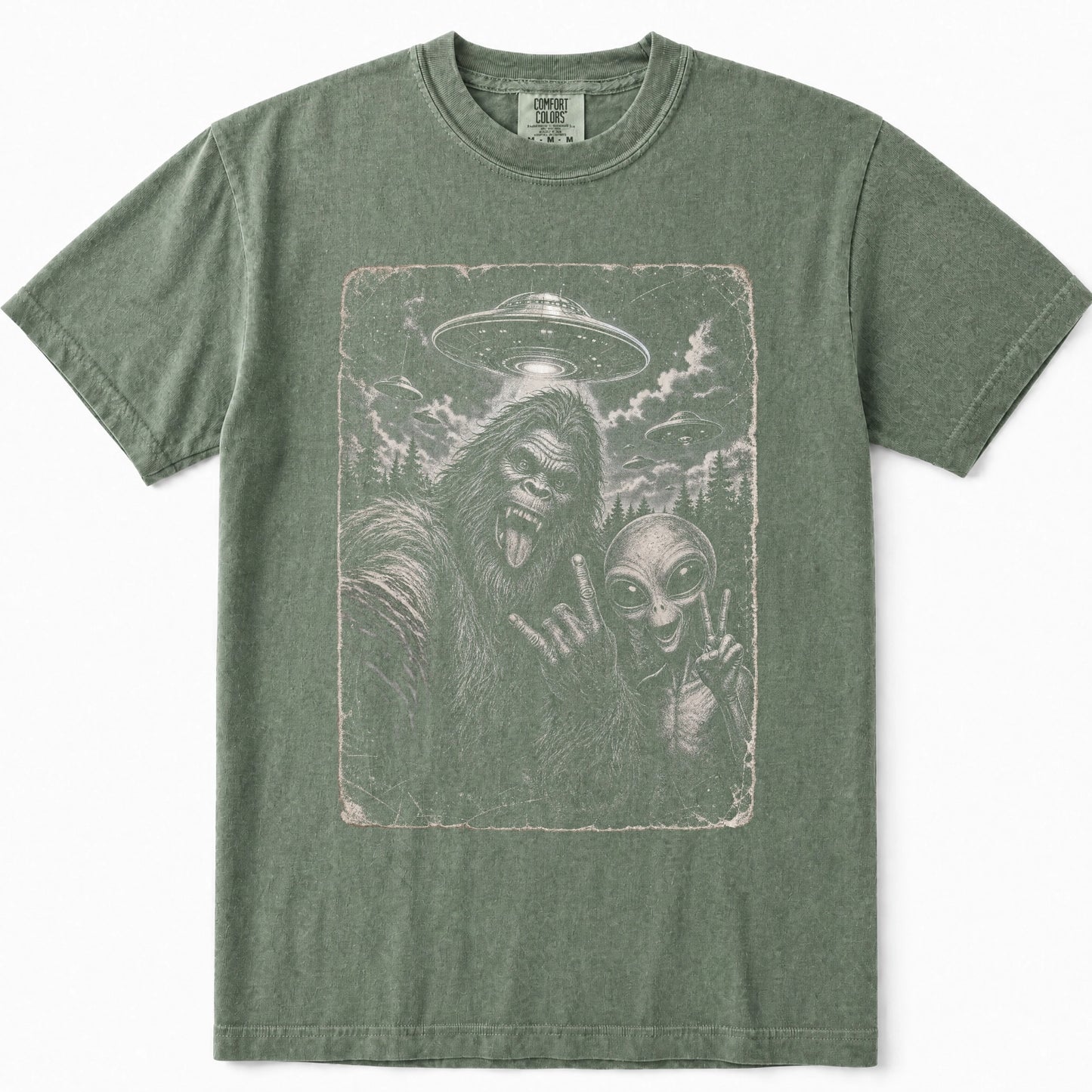 Moss green short-sleeve t-shirt featuring a distressed graphic print of Bigfoot and an alien in a UFO scene on the front.