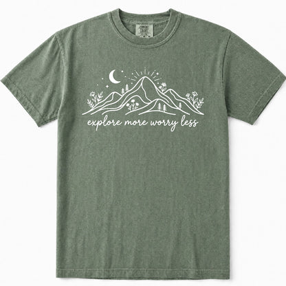 Moss green crewneck t-shirt with a white graphic of mountains, a crescent moon, and the text 'explore more worry less' printed on the chest.