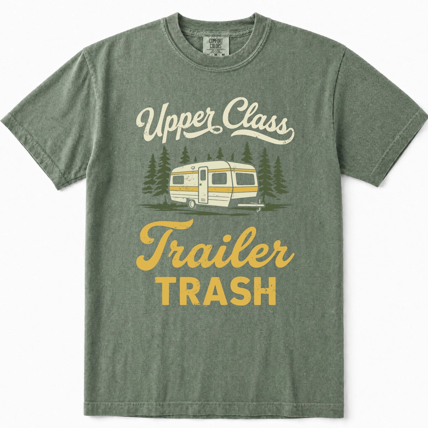 Moss green crewneck t-shirt featuring a retro graphic of a cream and yellow camper trailer surrounded by pine trees, with the text 'Upper Class Trailer TRASH' in cream and yellow lettering.
