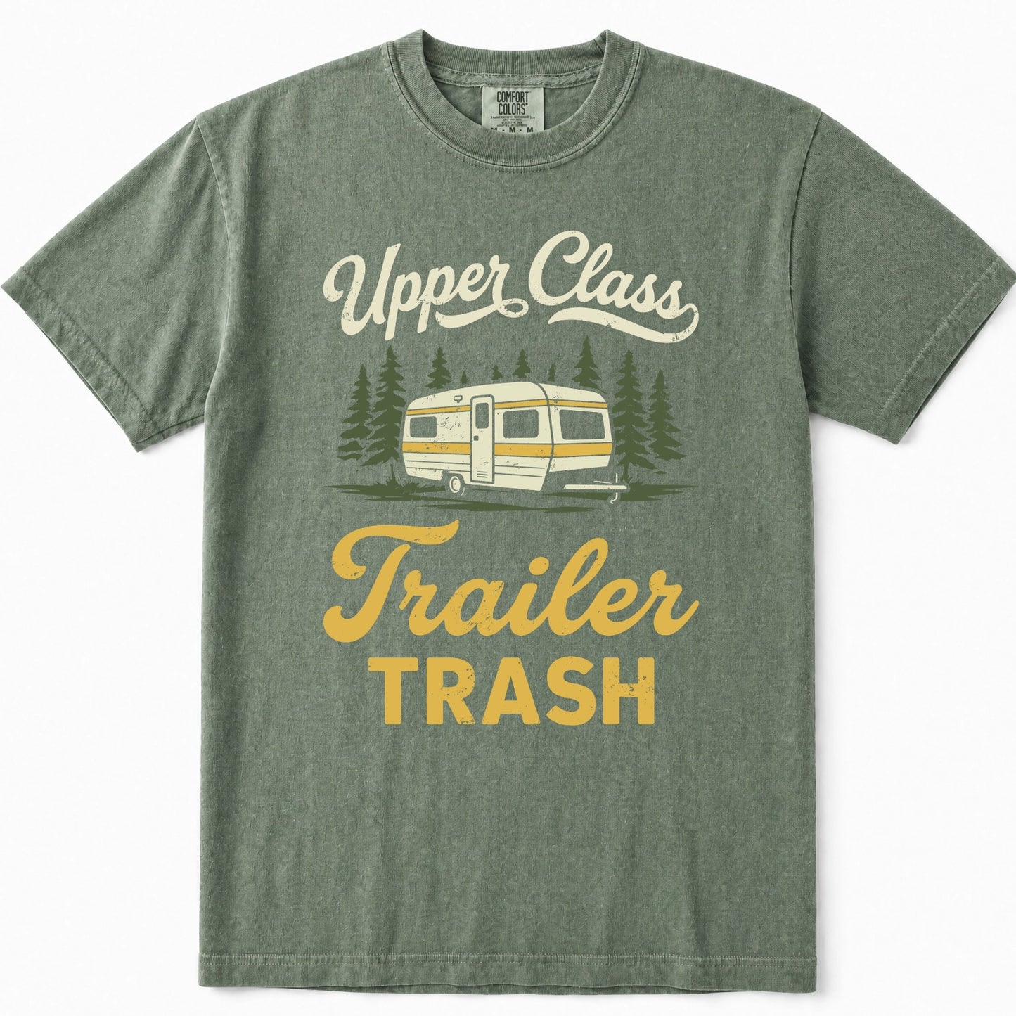 Moss green crewneck t-shirt featuring a retro graphic of a cream and yellow camper trailer surrounded by pine trees, with the text 'Upper Class Trailer TRASH' in cream and yellow lettering.