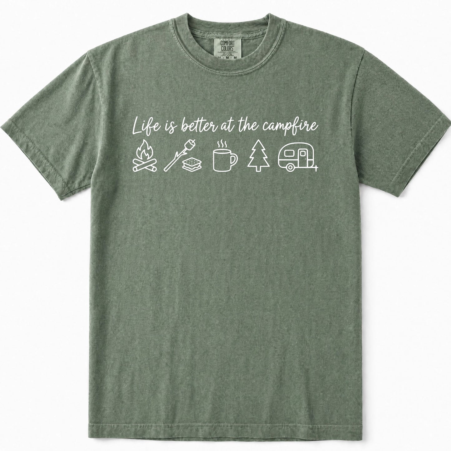 Moss green short-sleeve t-shirt with a white graphic print on the chest that reads 'Life is better at the campfire' above simple camping icons including a campfire, marshmallow, mug, tree, and camper. The shirt is displayed flat against a clean white background.
