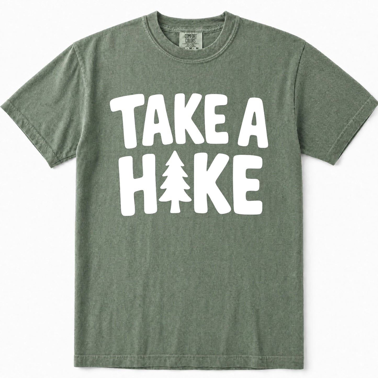 Moss green short-sleeve t-shirt with a bold white graphic print reading 'TAKE A HIKE' where the letter 'I' is replaced by a pine tree silhouette, shown flat against a white background.