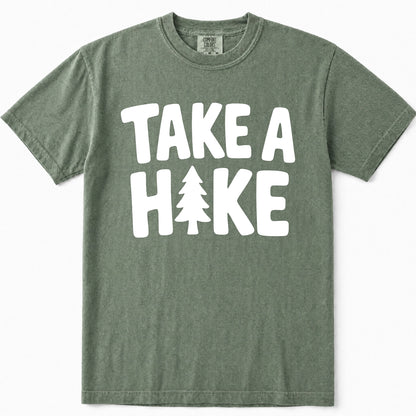 Moss green short-sleeve t-shirt with a bold white graphic print reading 'TAKE A HIKE' where the letter 'I' is replaced by a pine tree silhouette, shown flat against a white background.