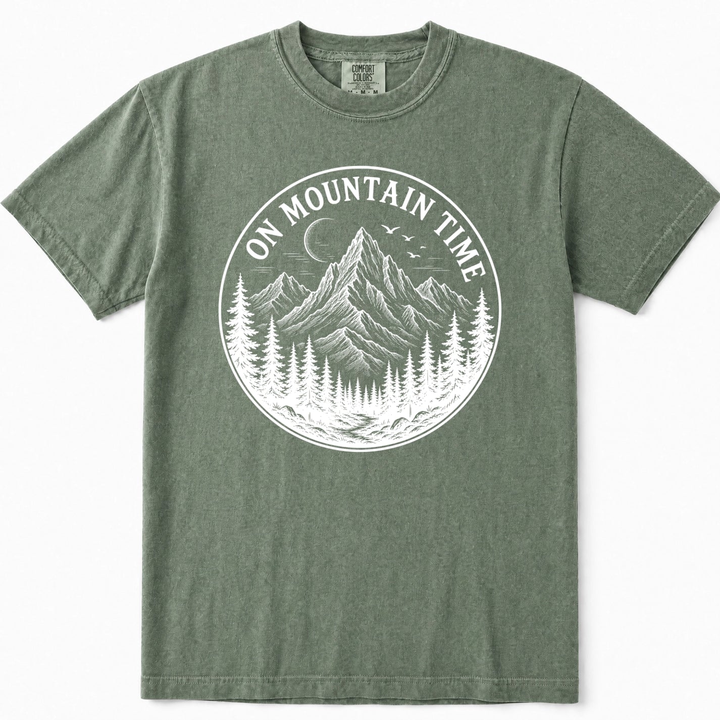 Moss green crewneck t-shirt featuring a large white circular graphic on the chest with a mountain, pine trees, and the text 'ON MOUNTAIN TIME'.