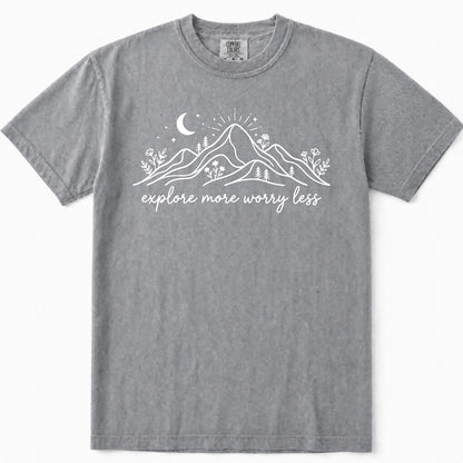 Grey short-sleeve crewneck t-shirt with a white graphic of mountains, a crescent moon, and the text 'explore more worry less' printed on the chest.