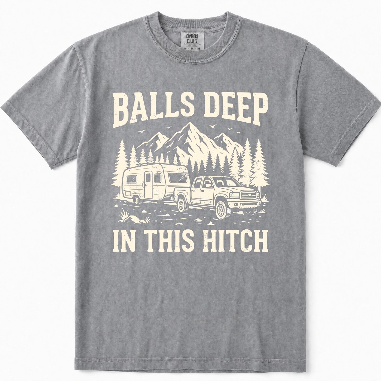 Grey crewneck t-shirt featuring a cream-colored graphic print of a pickup truck towing a camper trailer in front of mountains and pine trees, with the text 'BALLS DEEP IN THIS HITCH'.