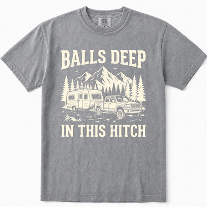 Grey crewneck t-shirt featuring a cream-colored graphic print of a pickup truck towing a camper trailer in front of mountains and pine trees, with the text 'BALLS DEEP IN THIS HITCH'.