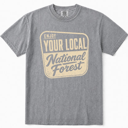 Grey short-sleeve t-shirt with a vintage-style graphic on the chest that reads 'ENJOY YOUR LOCAL National Forest' in cream and slate blue.