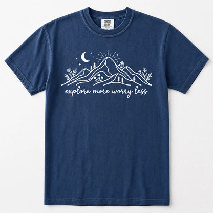 Navy blue short-sleeve crewneck t-shirt with a white graphic of mountains, a crescent moon, stars, and the text 'explore more worry less' printed on the front.