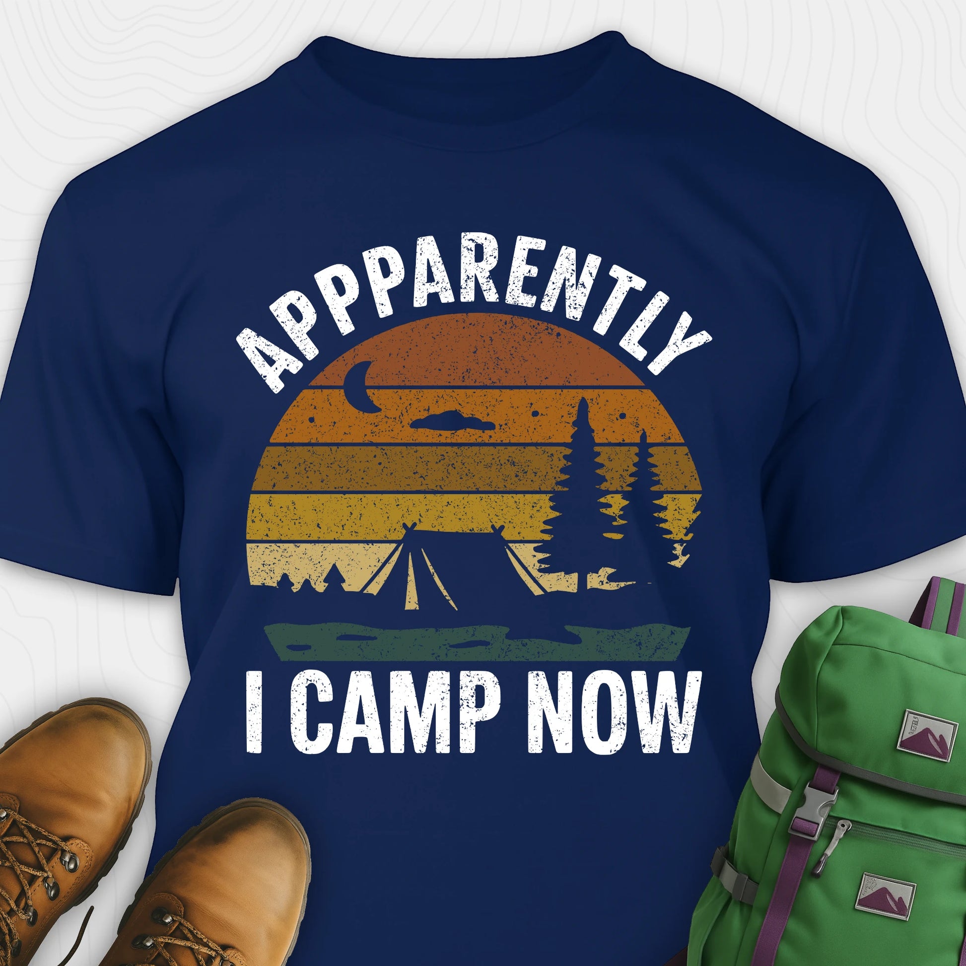 Navy t-shirt with “Apparently I Camp Now” in white text and a vintage sunset camping scene with tent, trees, and moon.