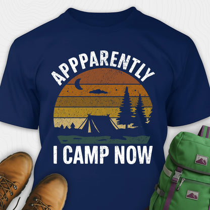Navy t-shirt with “Apparently I Camp Now” in white text and a vintage sunset camping scene with tent, trees, and moon.