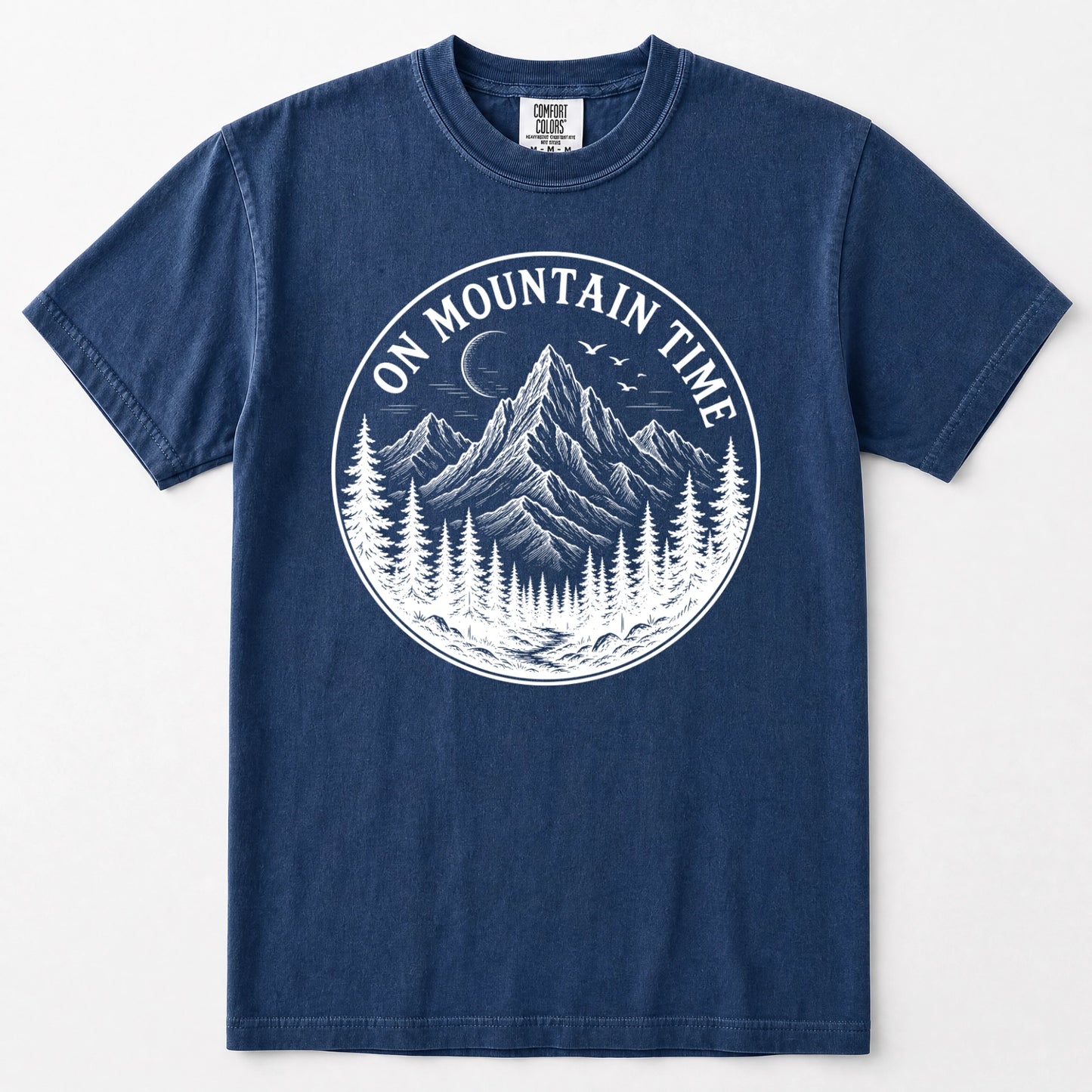 Navy blue short-sleeve t-shirt with a white circular graphic on the chest depicting a mountain, pine trees, birds, and a crescent moon, with the text 'ON MOUNTAIN TIME'.