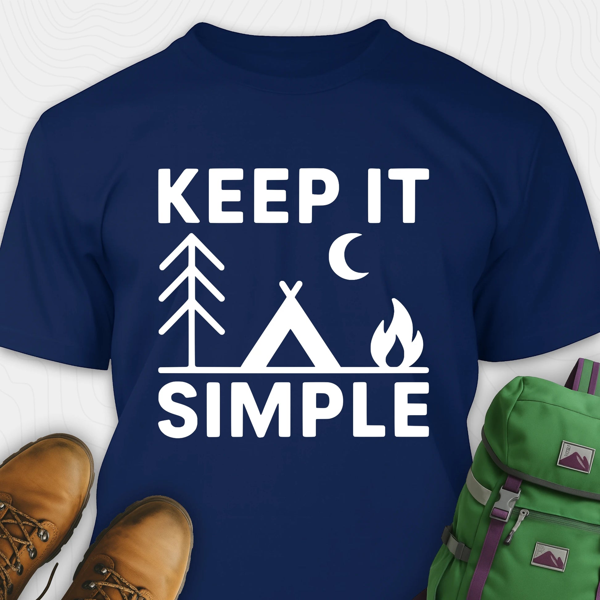 Navy keep it simple camping t-shirt with tent and campfire graphic with boots, and a backpack on either side on a white background