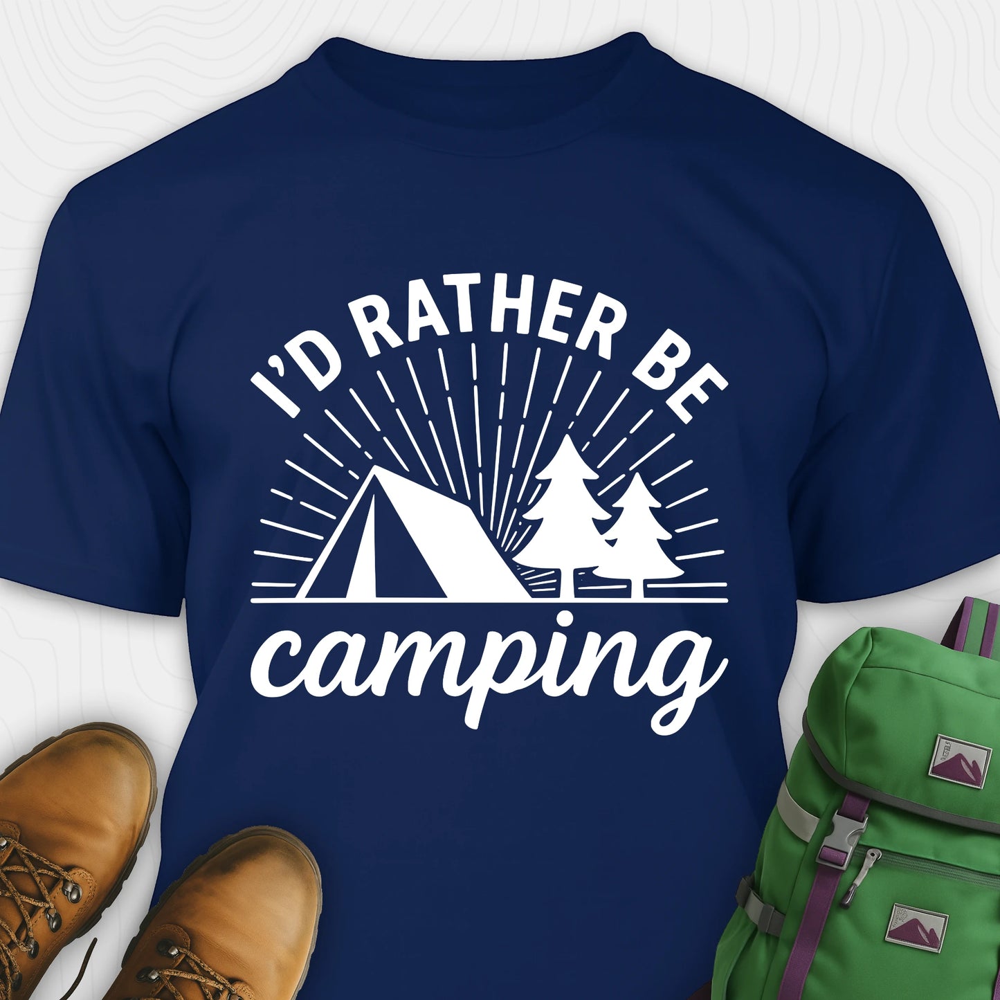Navy blue camping shirt with 'I'd Rather Be Camping' design, brown boots, and green backpack on a white background