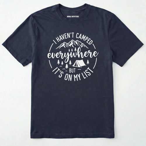 Navy funny camping shirt saying with mountains, trees, tent graphic and "I Haven't Camped Everywhere But It's On My List" text on a white background.