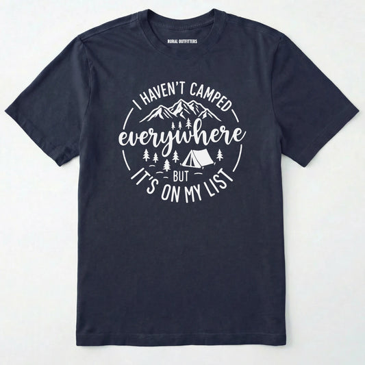 Navy funny camping shirt saying with mountains, trees, tent graphic and "I Haven't Camped Everywhere But It's On My List" text on a white background.
