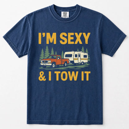 Navy blue crewneck t-shirt featuring a graphic print of an orange pickup truck towing a cream camper trailer, with the text 'I'M SEXY & I TOW IT' in yellow above and below the illustration.