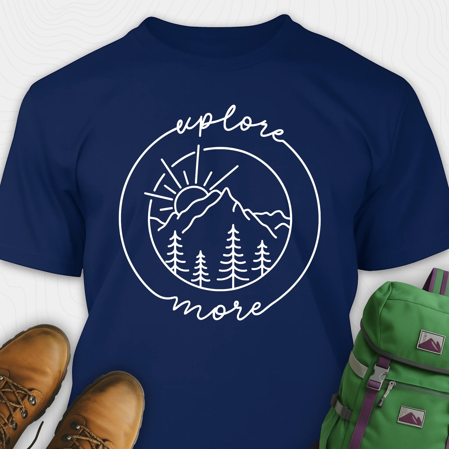 Navy blue explorer shirt with 'explore more' graphic design, brown boots, and green backpack on a white background