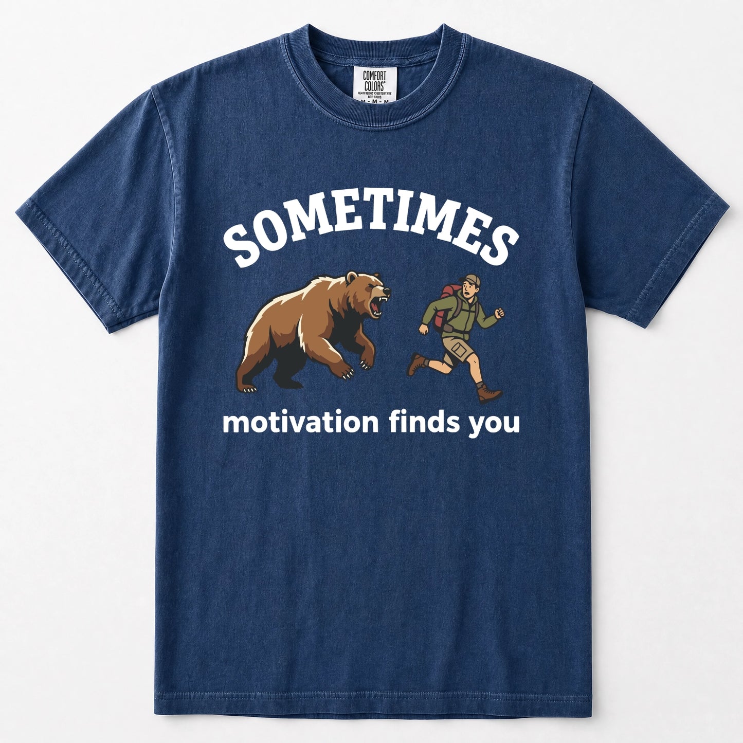 Navy blue short-sleeve t-shirt with a graphic print on the front. The print features the word 'SOMETIMES' in white arched text above an illustration of a brown bear and a running person, with the phrase 'motivation finds you' printed below in white.