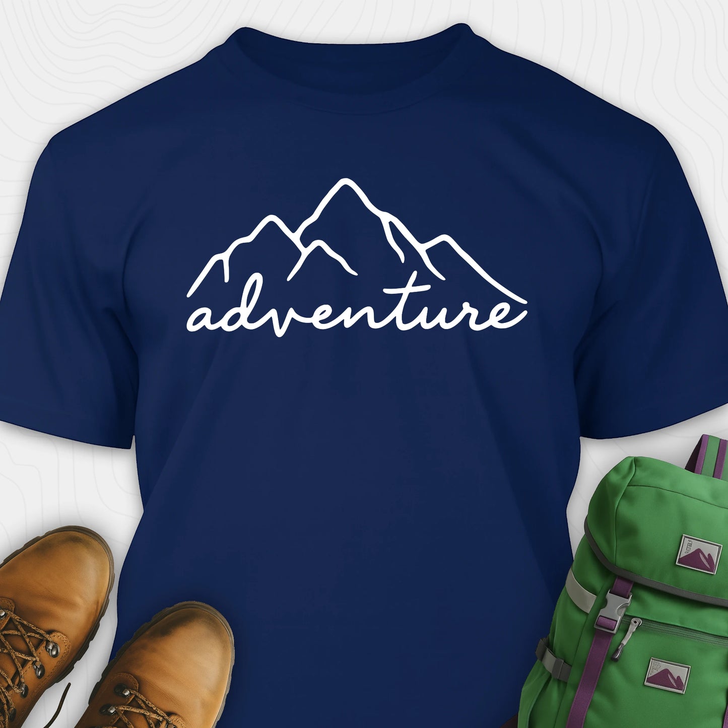 Navy blue adventure shirt with mountain design and 'adventure' text, paired with brown boots and a green backpack.