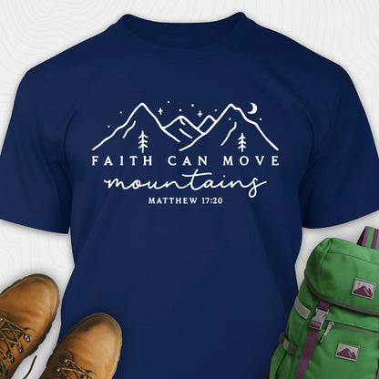 Navy faith can move mountains shirt with mountain scripture design, paired with hiking boots and a green backpack.