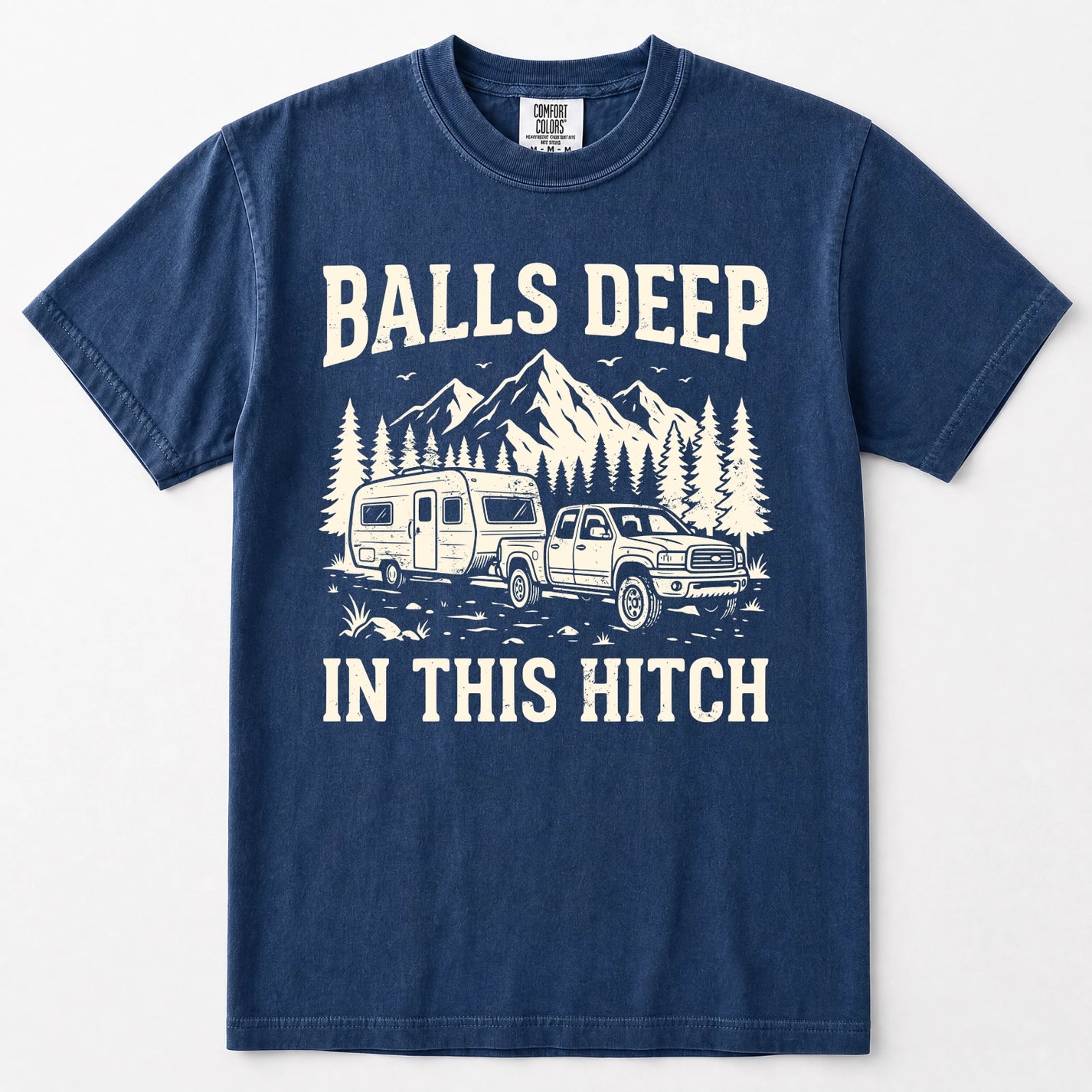 Navy blue short-sleeve crewneck t-shirt with a white graphic print on the front. The graphic features the text 'BALLS DEEP IN THIS HITCH' surrounding an illustration of a pickup truck towing a camper trailer with mountains and pine trees in the background.