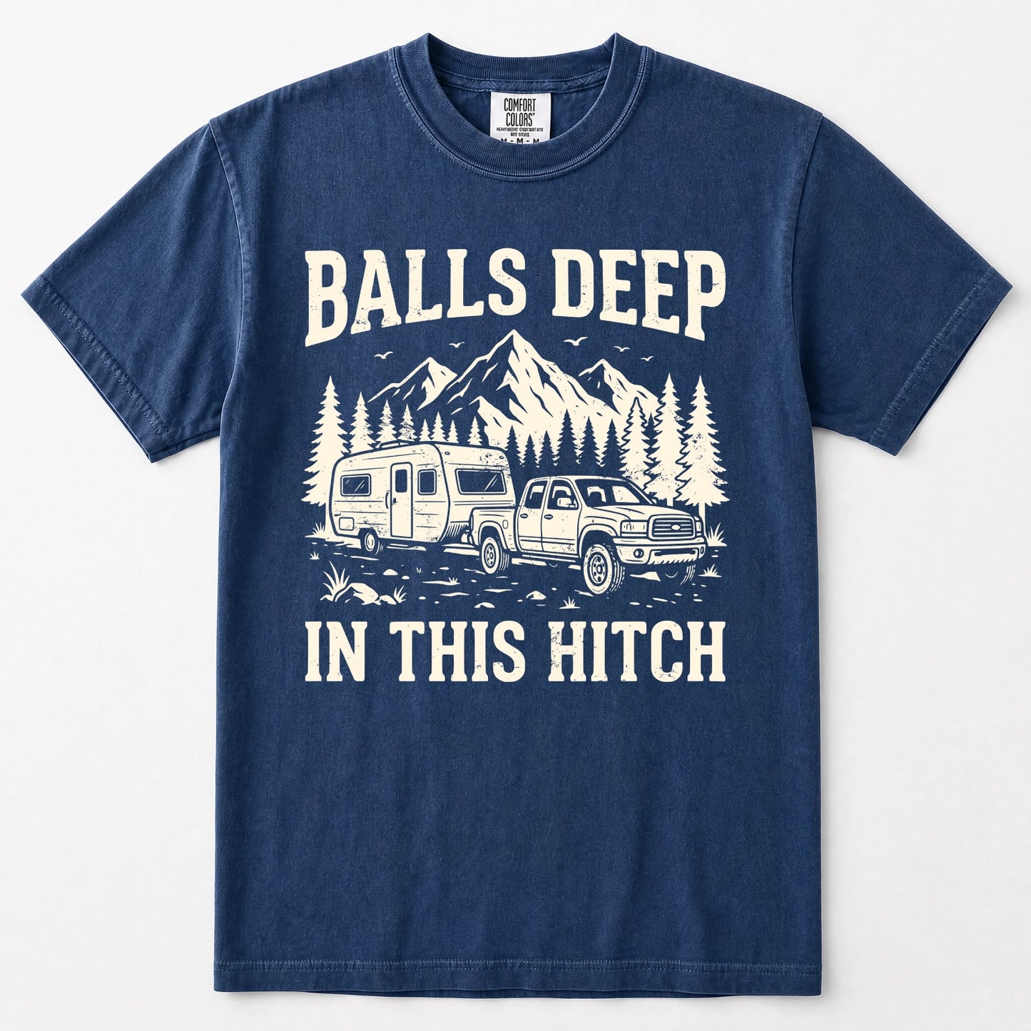 Navy blue short-sleeve crewneck t-shirt with a white graphic print on the front. The graphic features the text 'BALLS DEEP IN THIS HITCH' surrounding an illustration of a pickup truck towing a camper trailer with mountains and pine trees in the background.