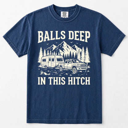 Navy blue short-sleeve crewneck t-shirt with a white graphic print on the front. The graphic features the text 'BALLS DEEP IN THIS HITCH' surrounding an illustration of a pickup truck towing a camper trailer with mountains and pine trees in the background.