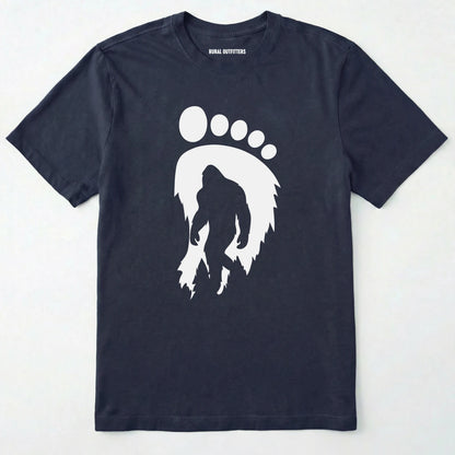 Navy bigfoot t-shirt with cryptid-themed footprint graphic and sasquatch silhouette on a white background.