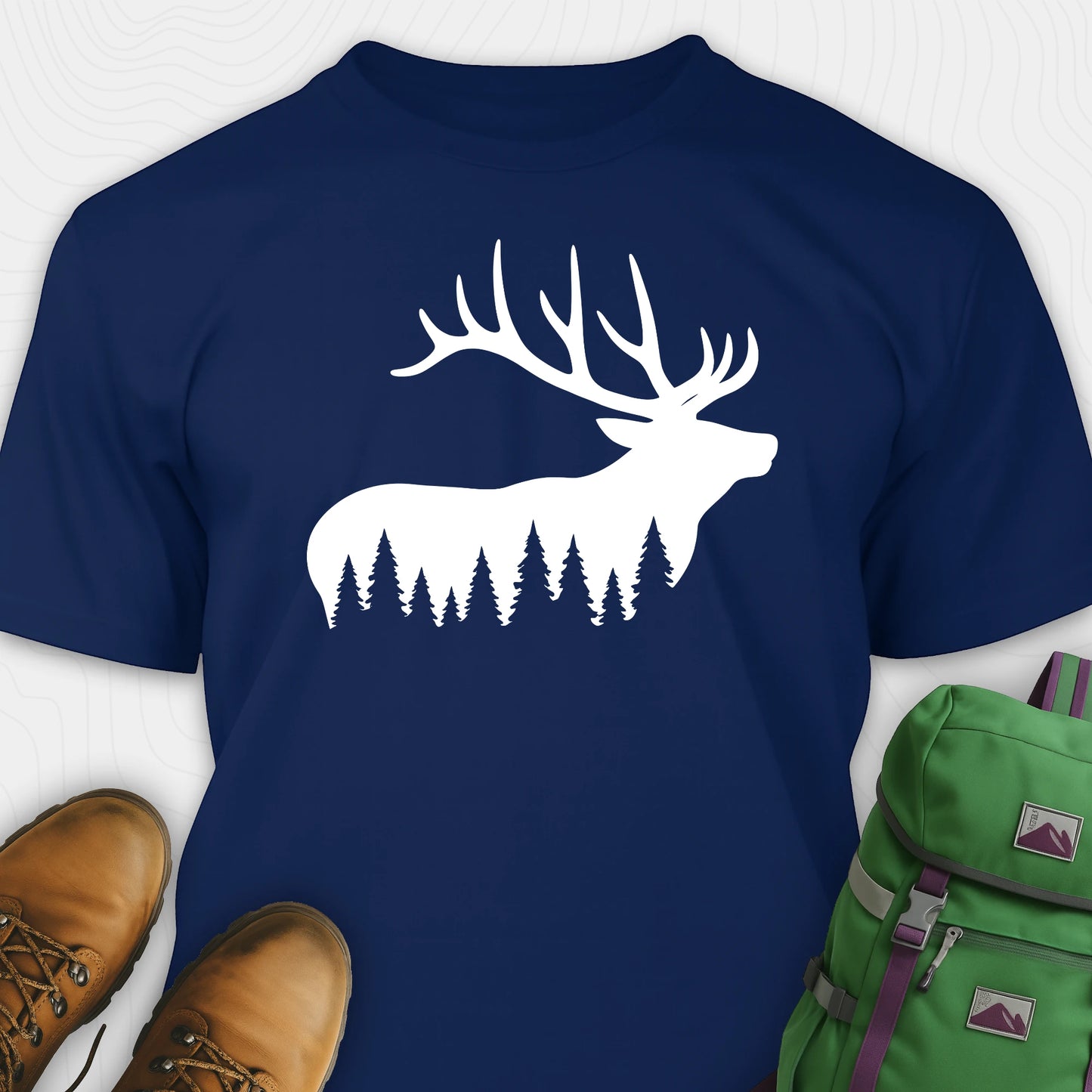 Navy elk shirt with black elk silhouette design, paired with brown boots and a green backpack on a white background.
