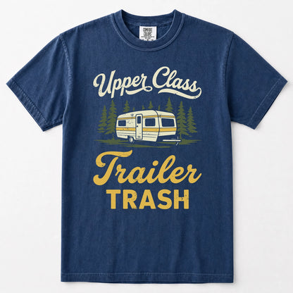 Navy blue short-sleeve t-shirt with a vintage-style graphic on the front featuring the text 'Upper Class Trailer TRASH' in white and yellow, alongside an illustration of a retro camper trailer and pine trees.