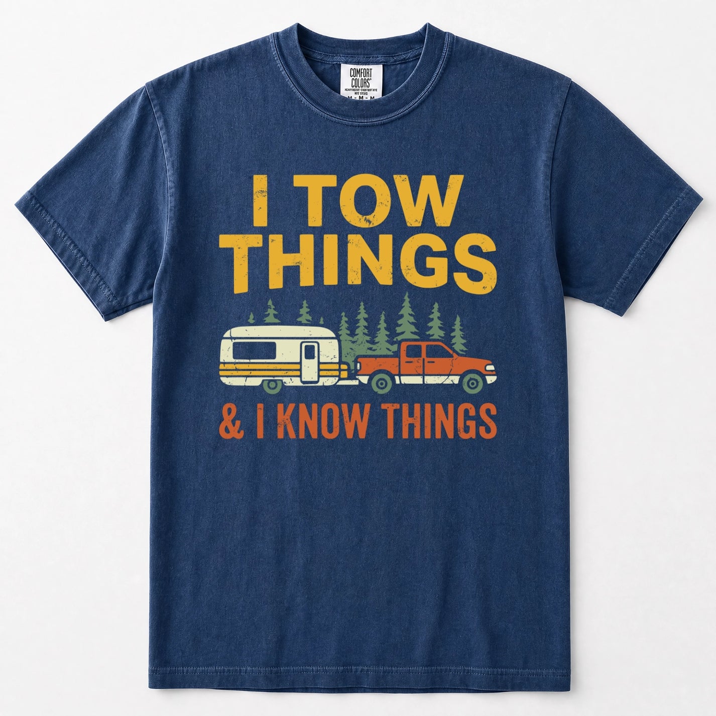 Navy blue short-sleeve t-shirt with a vintage-style graphic that reads 'I TOW THINGS & I KNOW THINGS' in yellow and orange text, featuring an illustration of a red pickup truck towing a white and yellow camper trailer with pine trees.