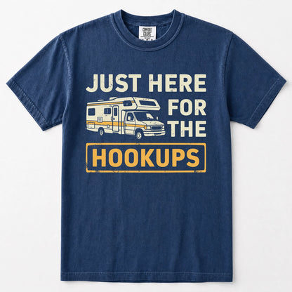 Navy blue short-sleeve t-shirt with a vintage-style graphic print featuring a camper van and the text 'JUST HERE FOR THE HOOKUPS' in distressed cream and yellow lettering, displayed on a clean white background.