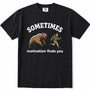 Black short-sleeve crewneck t-shirt with a graphic print on the front. The print features the word 'SOMETIMES' in white arched text above an illustration of a brown bear facing a small running person, with the phrase 'motivation finds you' printed below in white.