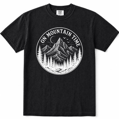 Black short-sleeve crewneck t-shirt featuring a circular white graphic print on the chest with a mountain, pine trees, and the text 'ON MOUNTAIN TIME'.