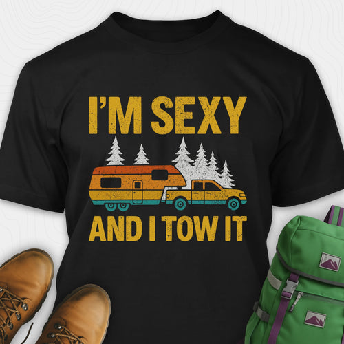 Black fifth wheel t-shirt with “I’m Sexy and I Tow It” in distressed yellow text and a retro truck towing a camper graphic.