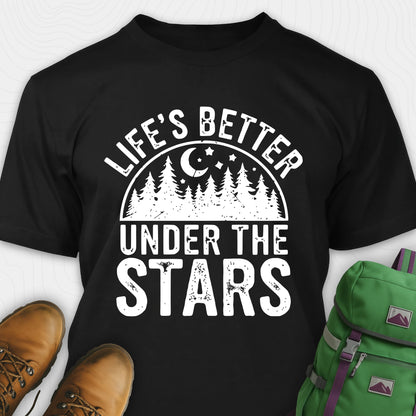 Black Life's Better Under the Stars t-shirt with forest and moon graphic, paired with brown boots and a green backpack on a white background.