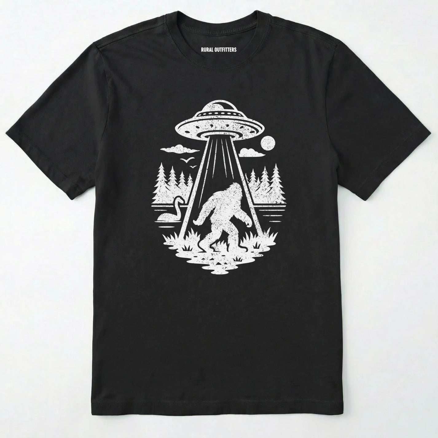 Black monster shirt with Bigfoot, a forest scene, and a UFO beam graphic on a white background.