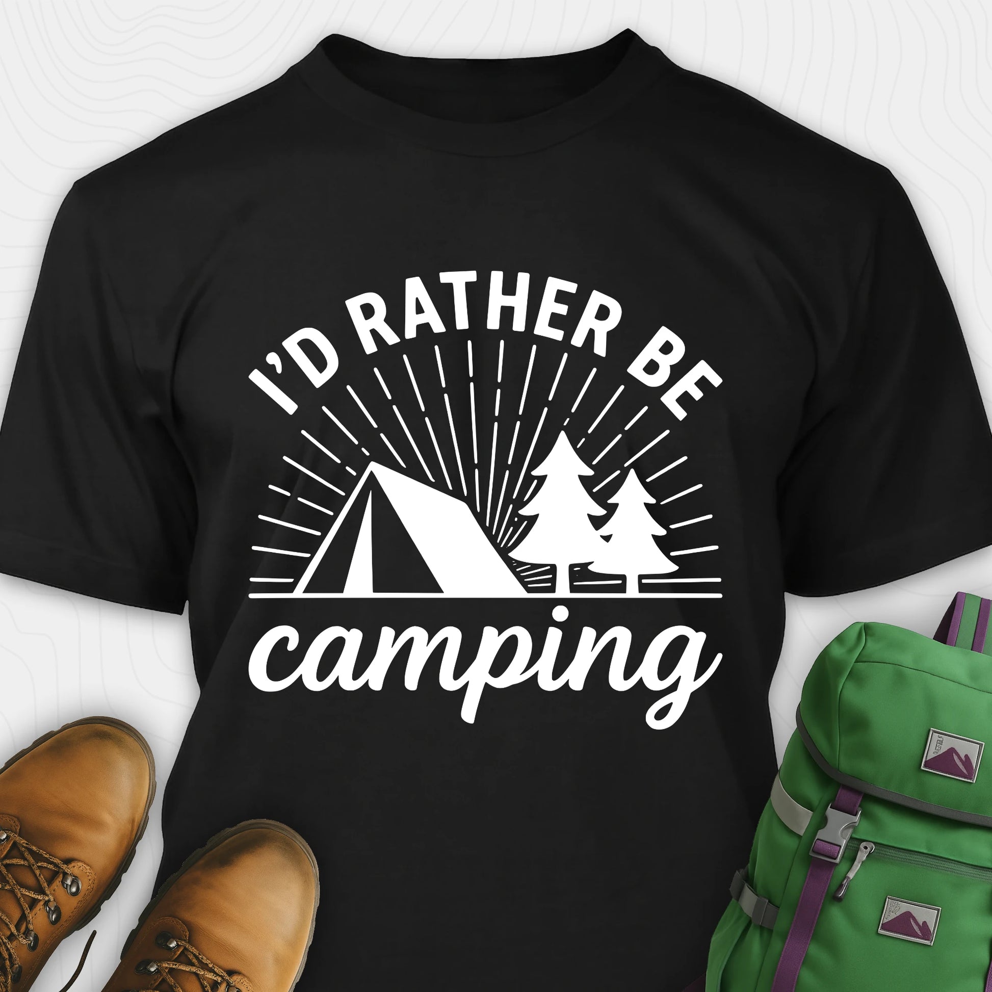 Black camping shirt with 'I'd Rather Be Camping' design, paired with brown boots and a green backpack on a white background.