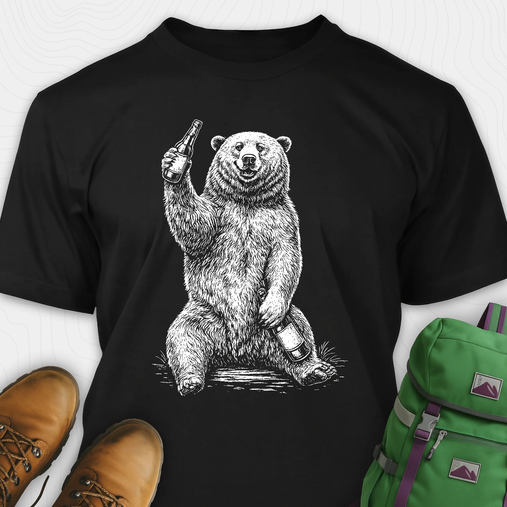 Black brown bear shirt with a bear graphic holding a beer bottle, paired with brown shoes and a green backpack on a white background.