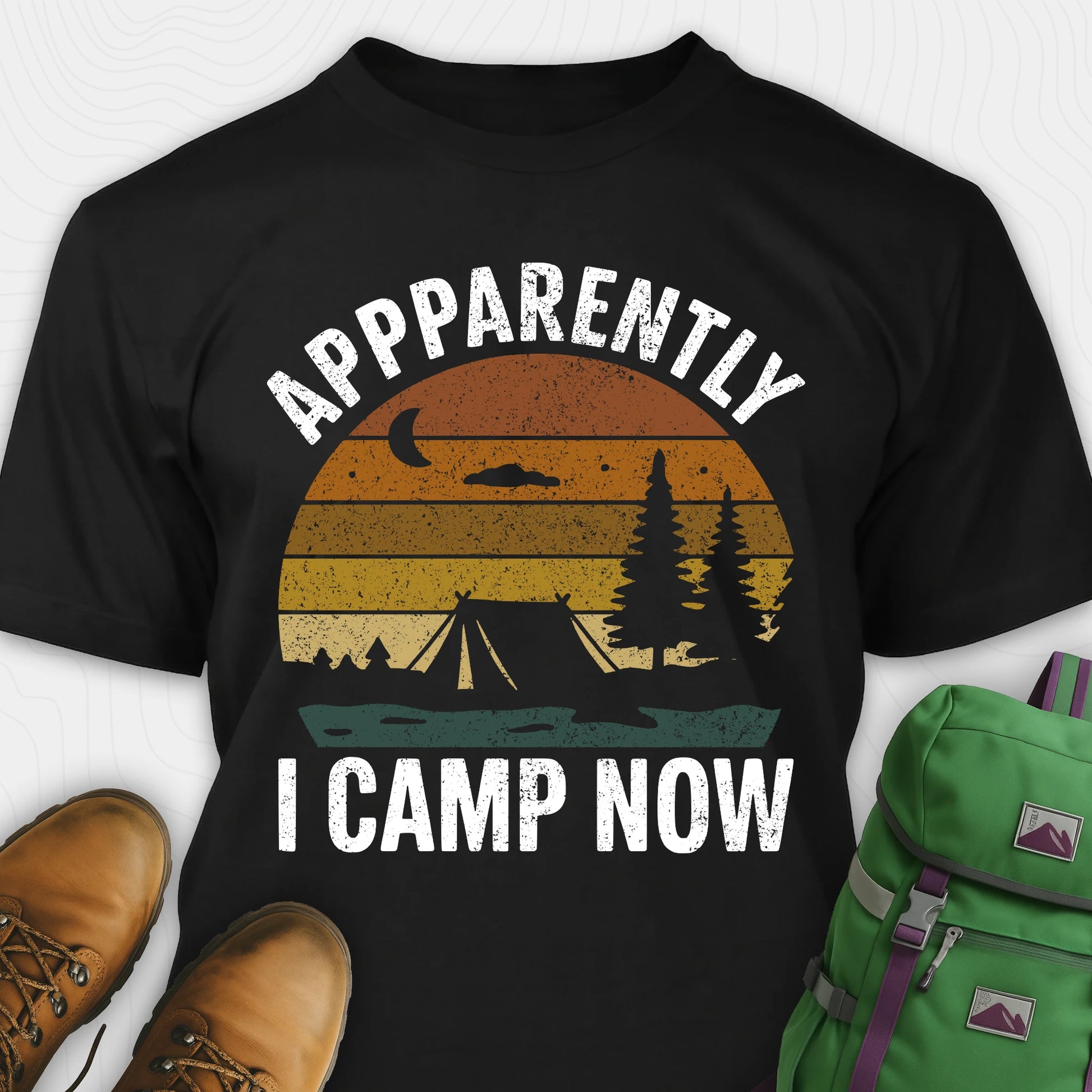 Black t-shirt with “Apparently I Camp Now” in white text and a vintage sunset camping scene with tent, trees, and moon.