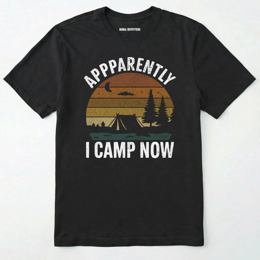 Black t-shirt with ⊜apparently i camp now⊝ in white text and a vintage sunset camping scene on a white background.
