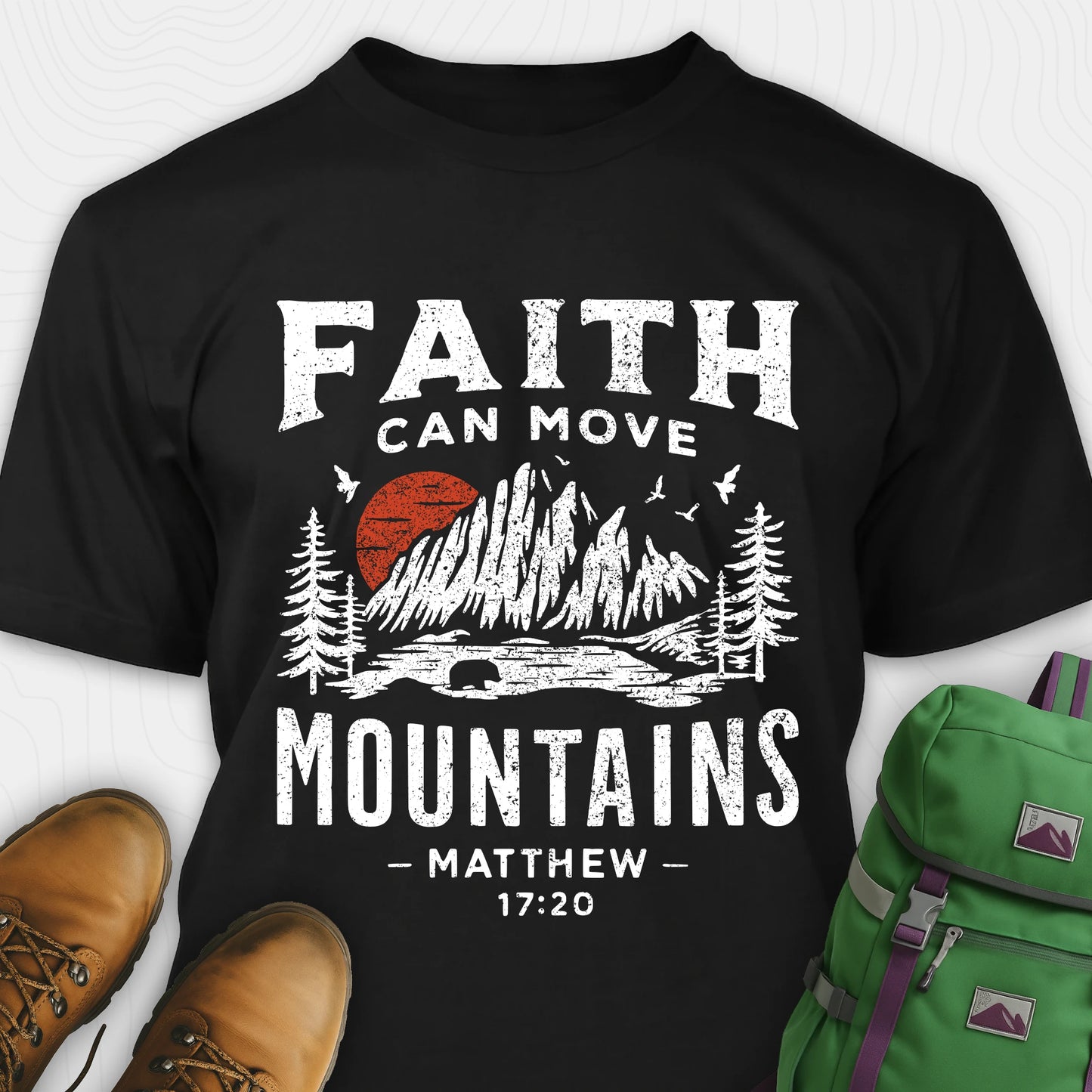 Black bible verse t-shirt with 'Faith can move mountains' design and hiking boots and backpack on a white background