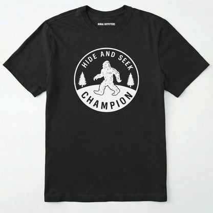 Black bigfoot hide and seek champion shirt with forest emblem on a white background.