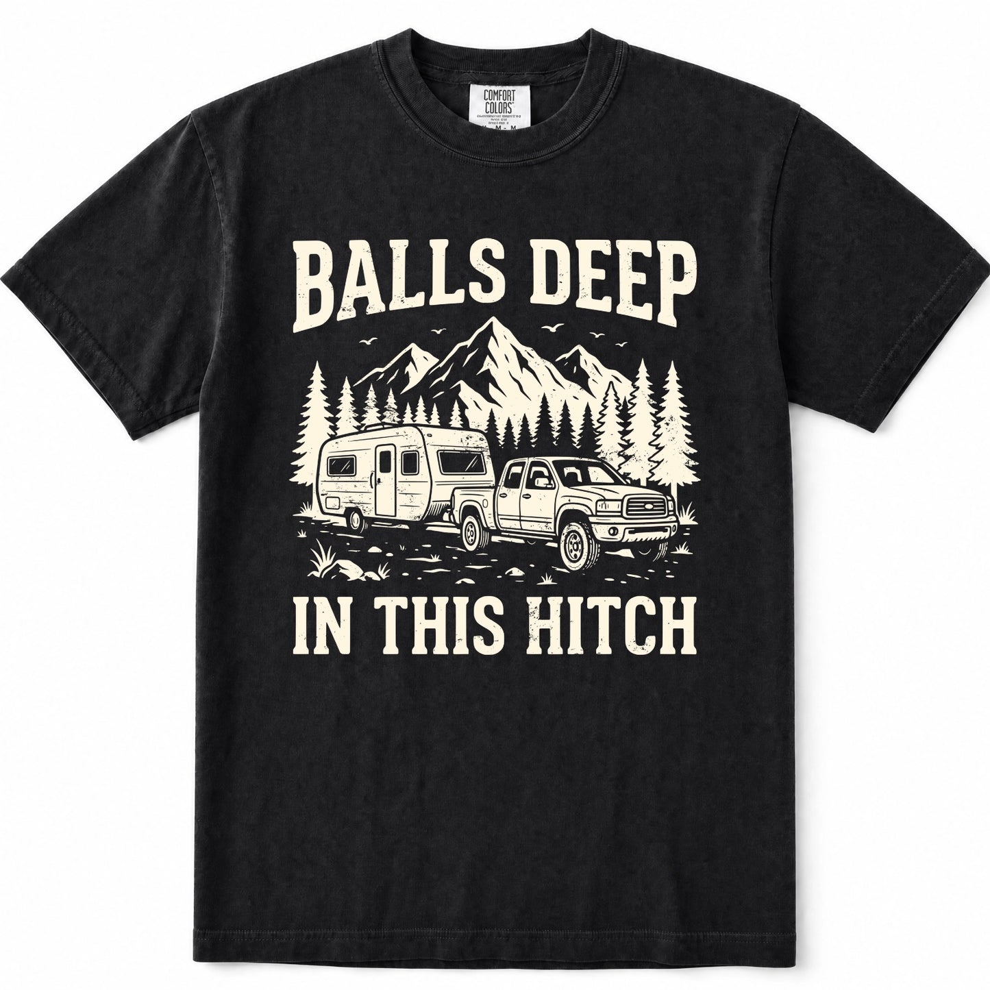 Black short-sleeve crewneck t-shirt with a vintage-style cream graphic showing a pickup truck towing a travel trailer in front of mountains and pine trees, with the text 'BALLS DEEP' above and 'IN THIS HITCH' below.