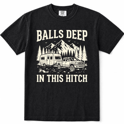 Black short-sleeve crewneck t-shirt with a vintage-style cream graphic showing a pickup truck towing a travel trailer in front of mountains and pine trees, with the text 'BALLS DEEP' above and 'IN THIS HITCH' below.
