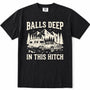 Black short-sleeve crewneck t-shirt with a vintage-style cream graphic showing a pickup truck towing a travel trailer in front of mountains and pine trees, with the text 'BALLS DEEP' above and 'IN THIS HITCH' below.