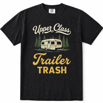 Black short-sleeve crewneck t-shirt with a vintage-style graphic print featuring the text 'Upper Class Trailer TRASH' in cream and yellow, alongside an illustration of a cream and yellow camper trailer surrounded by green pine trees.