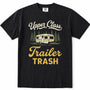 Black short-sleeve crewneck t-shirt with a vintage-style graphic print featuring the text 'Upper Class Trailer TRASH' in cream and yellow, alongside an illustration of a cream and yellow camper trailer surrounded by green pine trees.
