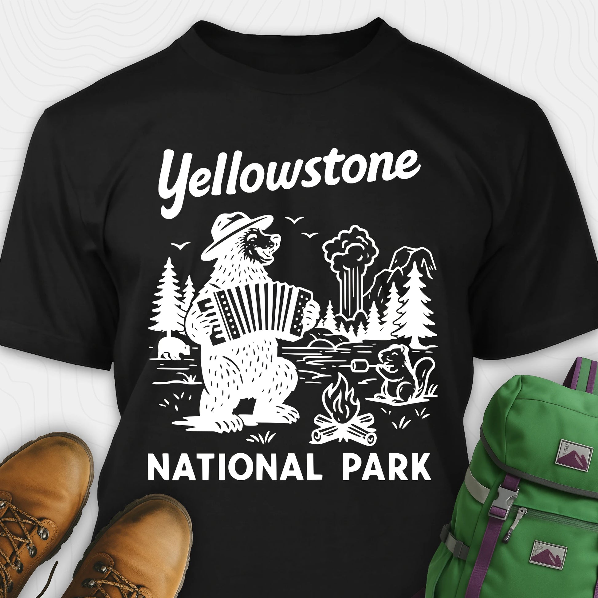 Black t-shirt with a brown bear playing an accordion and “Yellowstone National Park” text, styled with hiking boots and a green backpack.